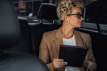 Obraz na płótnie Canvas Female Entrepreneur Looking Through Window While Sitting on Back Seat of a Luxury Car