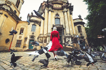 A girl in a red dress and flying doves near the Dominican Cathedral in the city of Lviv. Ukraine
