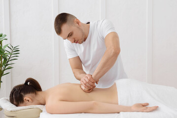 Obraz na płótnie Canvas Young pretty woman having back massage in spa, white background. Copy space, closeup
