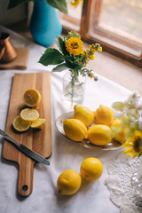 Picturesque composition on the table in a village house. Harvest lemon for cooking dishes from it. And yellow sunflowers in a blue vase. Ukrainian composition in the colors of the flag.