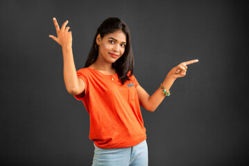 Portrait of a successful cheerful young girl pointing and presenting something with hand or finger with a happy smiling face.