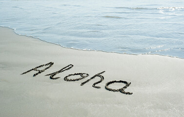 Concept or conceptual Aloha text handwritten in sand on a beach with waves  in an exotic island for...
