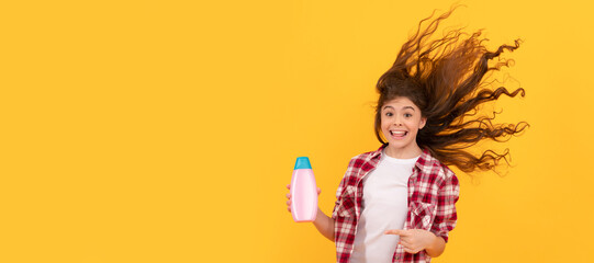 kid use shower gel. happy teen girl with shampoo bottle. shampooing hair in salon. Banner of child girl hair care, studio poster header with copy space.