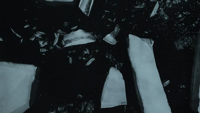 Slow motion shot of ice breaking on black background.
