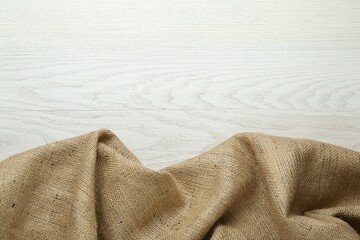 Natural burlap fabric on white wooden table, top view. Space for text