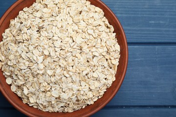Bowl of oatmeal on blue wooden table, top view