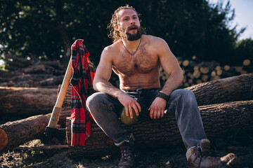 Man sitting on a log and drinking water in the forest - Powered by Adobe
