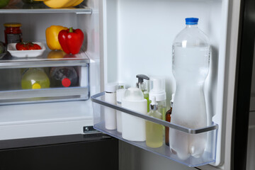 Storage of cosmetics and water in refrigerator door bin next to groceries