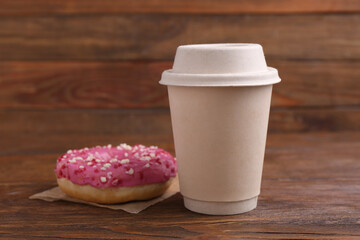 Tasty frosted donut with sprinkles and hot drink on wooden table