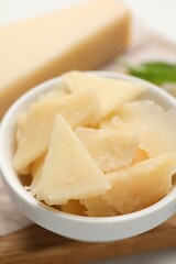 Bowl with parmesan cheese pieces on table, closeup