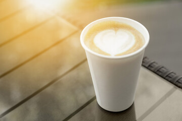 Cardboard takeaway cup of coffee on glass table outdoors, space for text