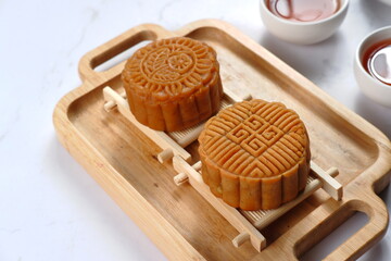 Mooncake, Moon cake-Round shaped Chinese traditional pastry with tea cups on white background,...