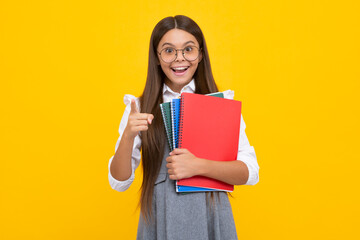 Back to school. Teenager schoolgirl with book ready to learn. School girl children on isolated yellow studio background. Excited face, cheerful emotions of teenager girl.