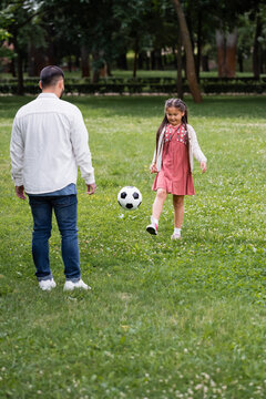 Asian kid playing soccer with papers in summer park.