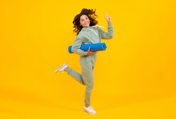 Girl teenager in tracksuit. Run and jump. Happy cute child in a yellow sports suit on a yellow background. Sportswear advertising concept.