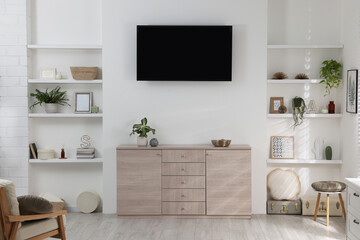 Stylish TV set mounted on wall in room