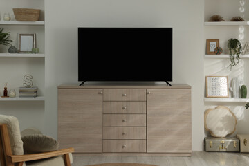 Stylish wide TV set on wooden cabinet in room