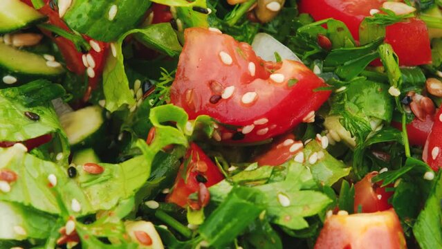 Concept of healthy nutrition and delicious food. Vegetarian salad of fresh vegetables with spices and olive oil. Finely chopped cucumbers tomatoes and green lettuce leaf with seasonings close up.