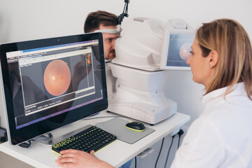 man checking his eye sight on retina scanner in clinic - obrazy, fototapety, plakaty