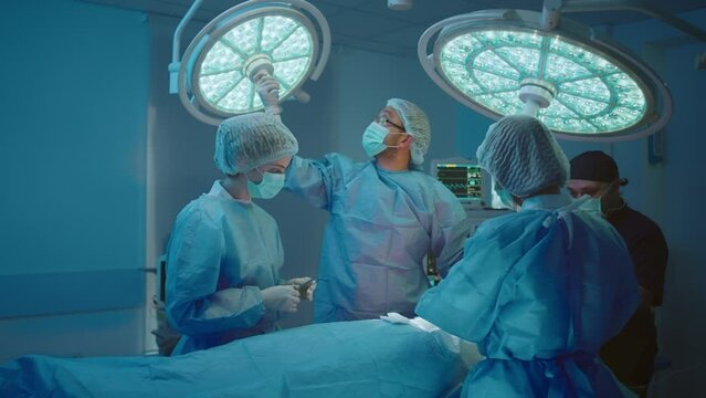 A medical surgeon is fixing a headlight and adjusting it so he can have perfect lighting for his surgery, the nurses are standing around him. Shot on ARRI