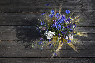 A bouquet of meadow wild flowers, top view, on a dark wooden background