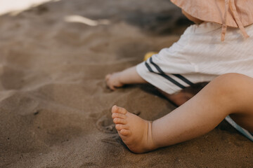 Baby playing in the sand, barefoot, closeup.