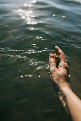 female hand touching calm water in the sea