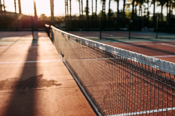 Closeup of a net on a tennis court in sunrise sun light, outdoors.
