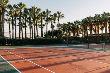 Empty tennis court in sunrise sun light, outdoors. - obrazy, fototapety, plakaty