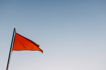 Red flag waving on a blue sky background.