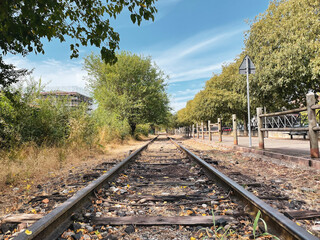 Fototapeta premium Old abandoned rails. Remains of an old railway in the center of a small town. Perspective, parallel lines and deserted places.