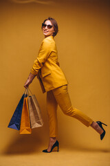 Woman with shopping bags in studio on yellow background isolated