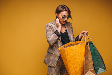 Woman with shopping bags in studio on yellow background isolated