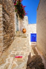 A picturesque alley on the Greek island Hydra. White washed wall, limestone house, terracota decoration and bougainvillea tree.  