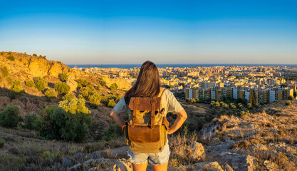 Digital nomad girl looking at the city of Malaga at sunset.