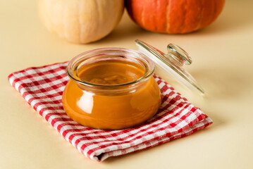 Pumpkin Puree with Fresh Pumpkins and Spices in Glass Bowl on Linen Cloth Autumn Food Yellow Background