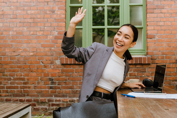 Asian young woman working with laptop while sitting in cafe