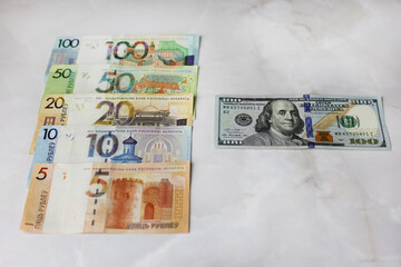 Banknotes in denominations of 100,50,20,10.5 belarusian rubles and 100 dollars on an grey background