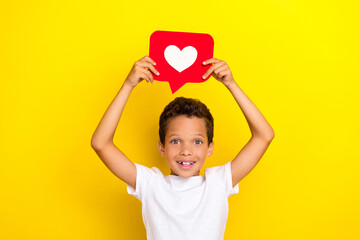 Photo of funny little boy hold heart wear white t-shirt isolated on yellow color background