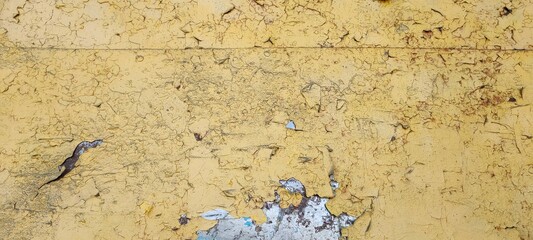 An old wall with peeling yellow paint. Abstract textured wall background.