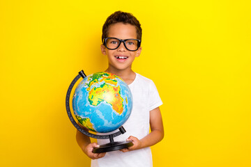 Photo of positive cheerful boy student first lesson hold globe earth isolated on yellow color background