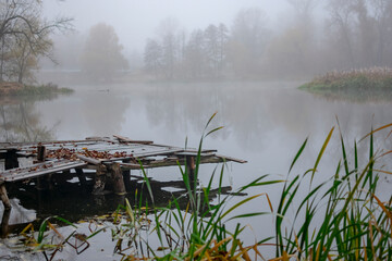 Fototapeta na wymiar Early foggy morning on the river with a fishing bridge.