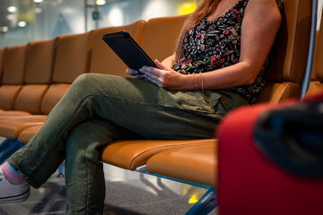 Mujer haciendo tiempo en sala de espera leyendo un libro digital en su tablet
