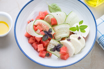 Salad with watermelon cubes, cucumber slices, cheese and basil, middle close-up, selective focus
