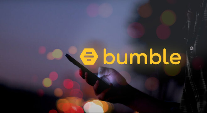 bumble logo above a hand holding a smartphone with screen glowing at night, red, orange and yellow dots of light, romantic, dating, flirt, love