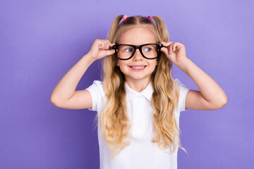 Photo of charming small girl tails arms touch eyewear oculist checkup dressed stylish white blouse isolated on violet color background