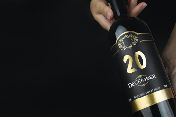 December 20th. Day 20 of month, Calendar date. Hands hold bottle of red wine with a calendar date on label.  Winter month, day of the year concept.