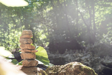 A stack of zen rocks are in the forest with trees in the background
