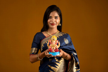 Happy young Indian woman posing with Ganesha statue on the occasion of Ganesh Festival