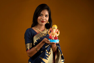 Happy young Indian woman posing with Ganesha statue on the occasion of Ganesh Festival